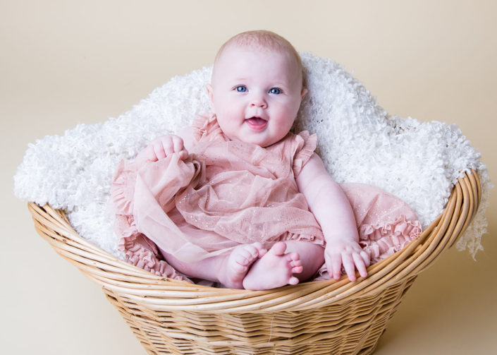 Happy baby in basket with yellow photographic background