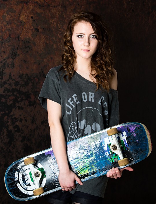 Teenager hold skateboard. An example of a portrait taekn within a family session, using a prop.