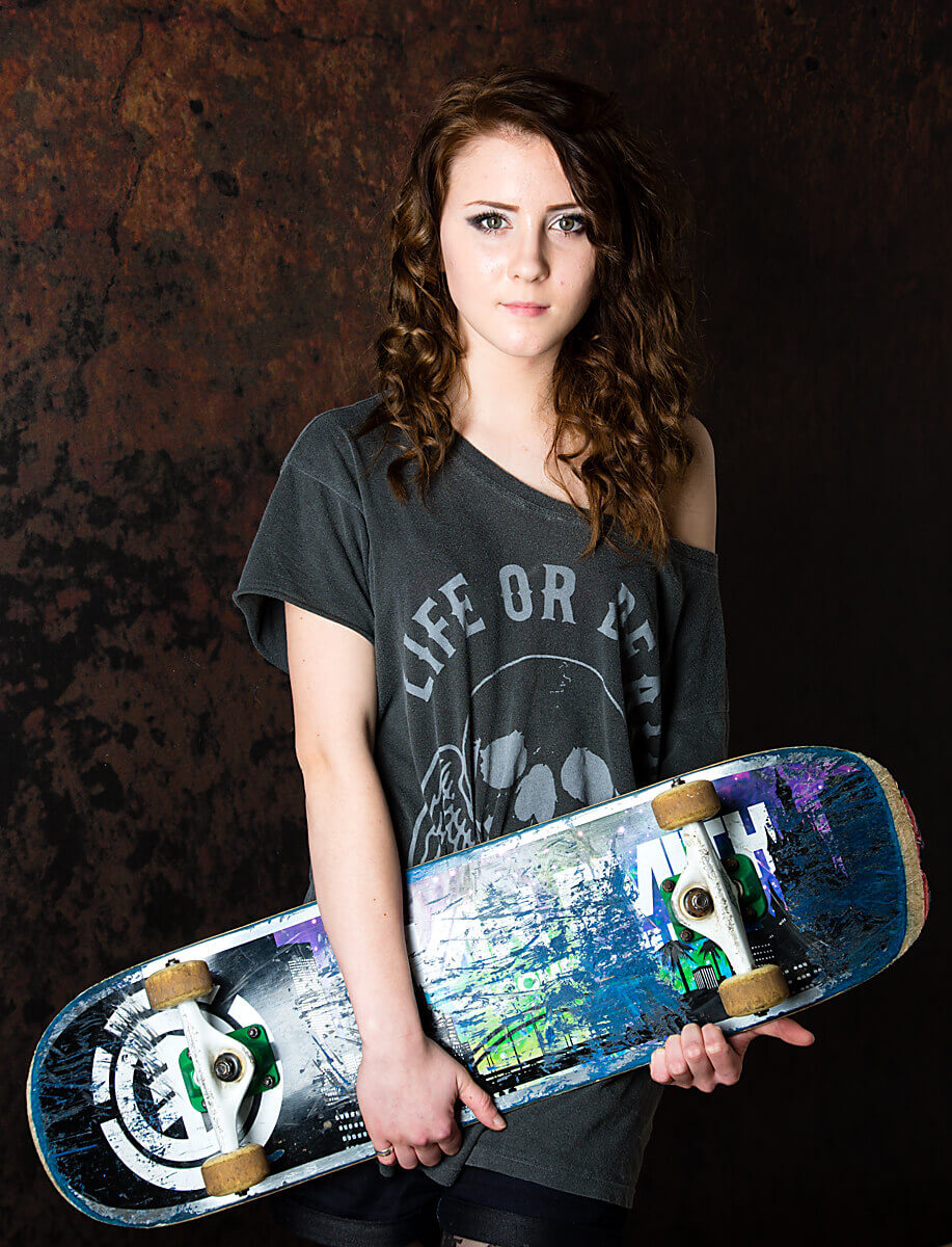 What to wear: Teenager hold skateboard. An example of a portrait taken within a family session, using a prop.