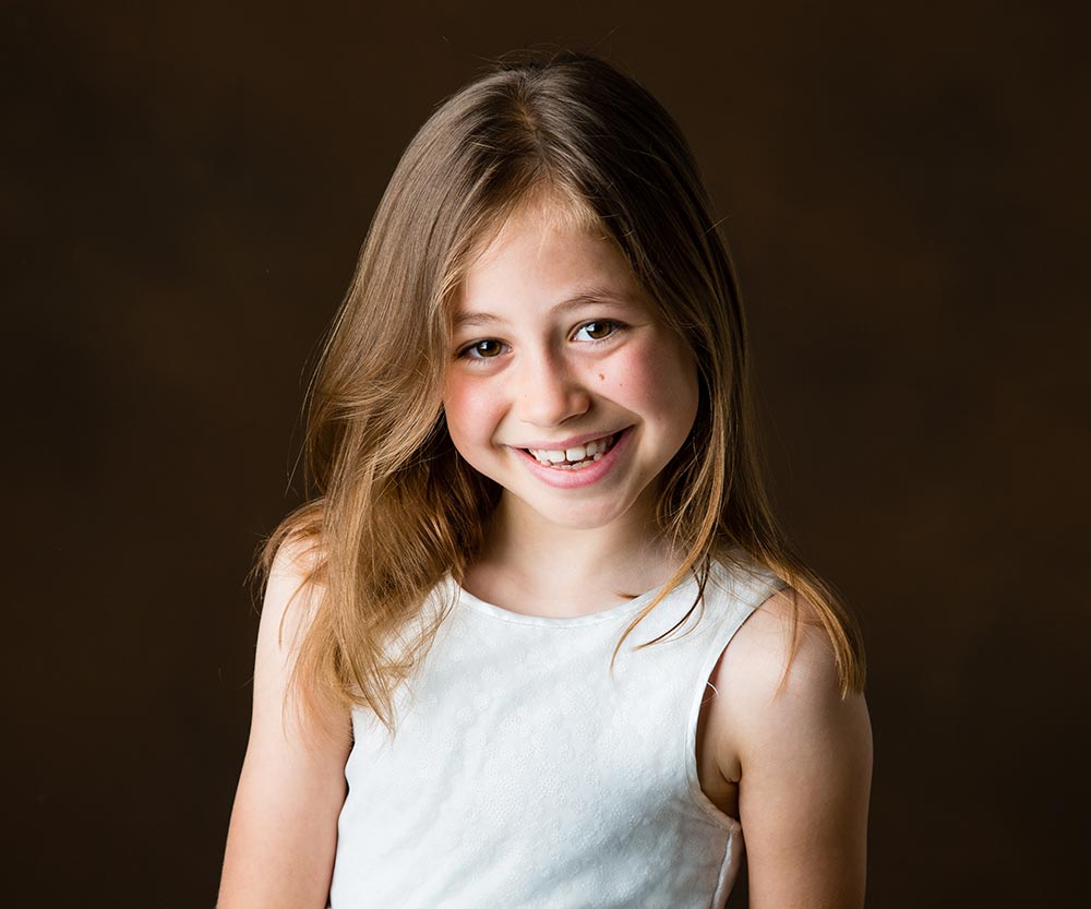 Smiling girl in front of brown backdrop in photography studio