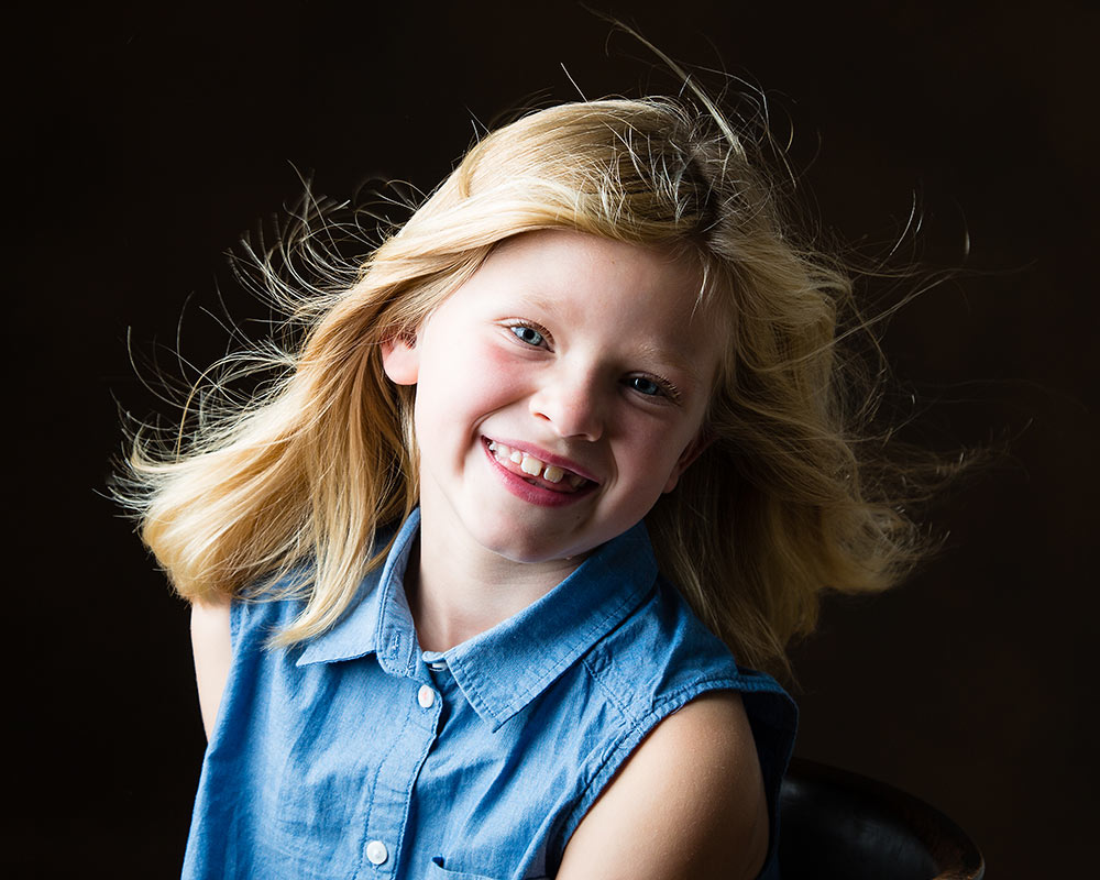 Blond girl with wind machine in family studio