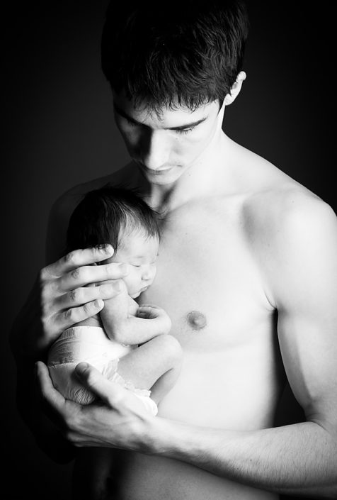 Newborn baby sleeping against father's bare skin